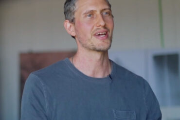 Kamran Samimi wearing a blue cotton long sleeve talking about his artwork