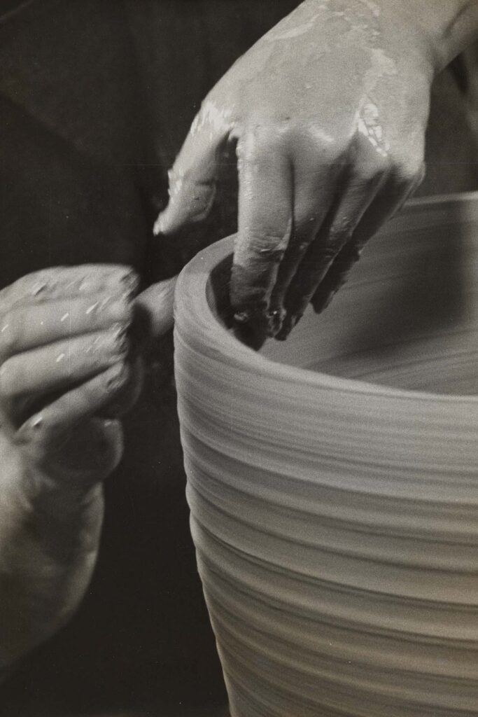a close-up of hands making a clay pot
